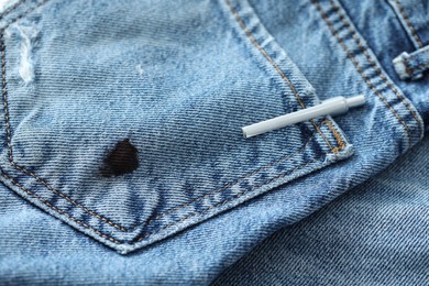 Photo of Pen and stain of black ink on jeans, closeup