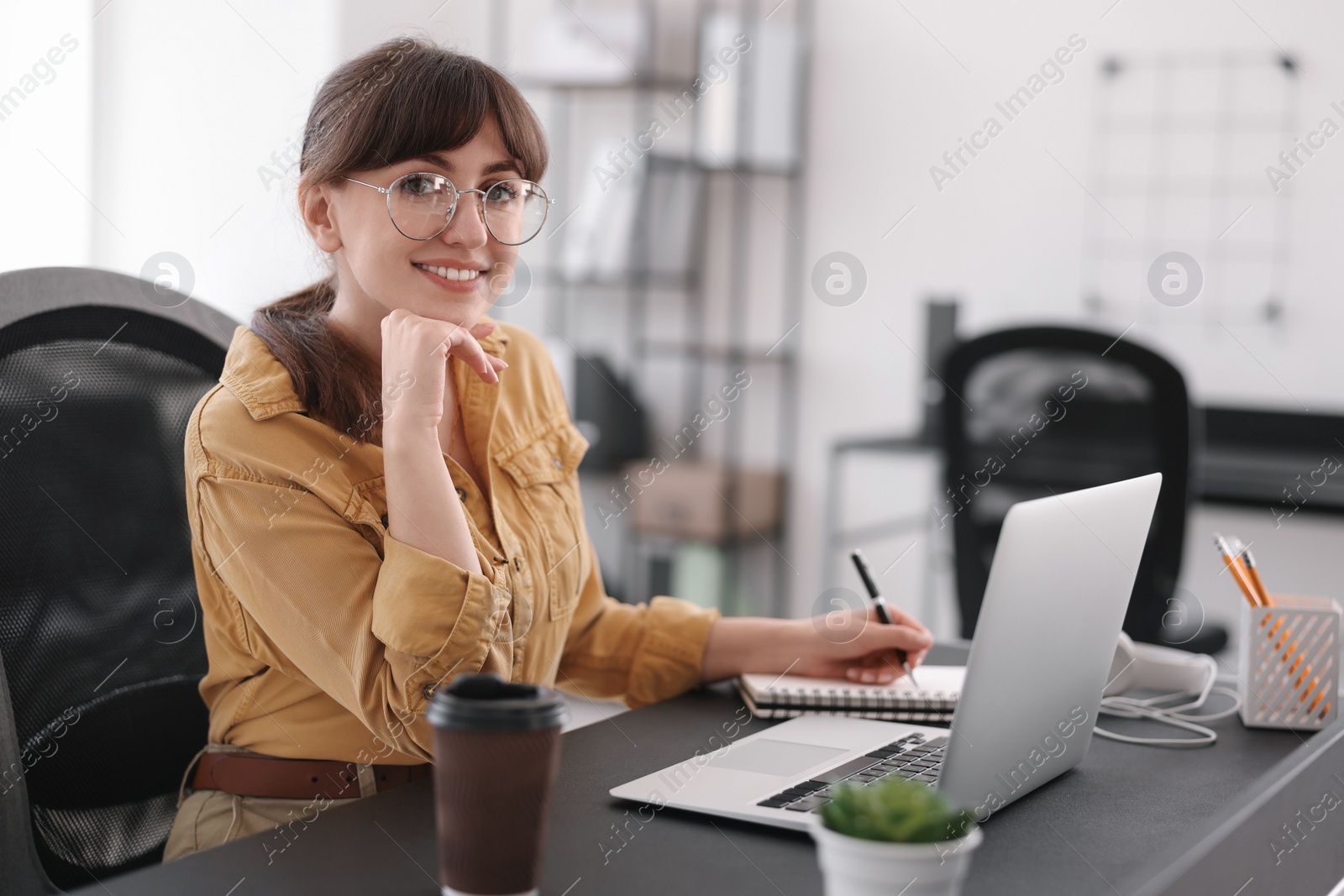 Photo of Woman taking notes during webinar at table indoors