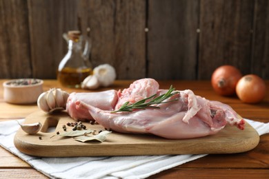 Photo of Fresh raw rabbit meat and spices on wooden table