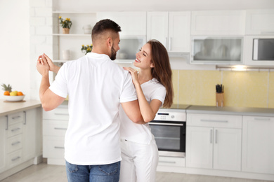 Lovely young couple dancing in kitchen at home
