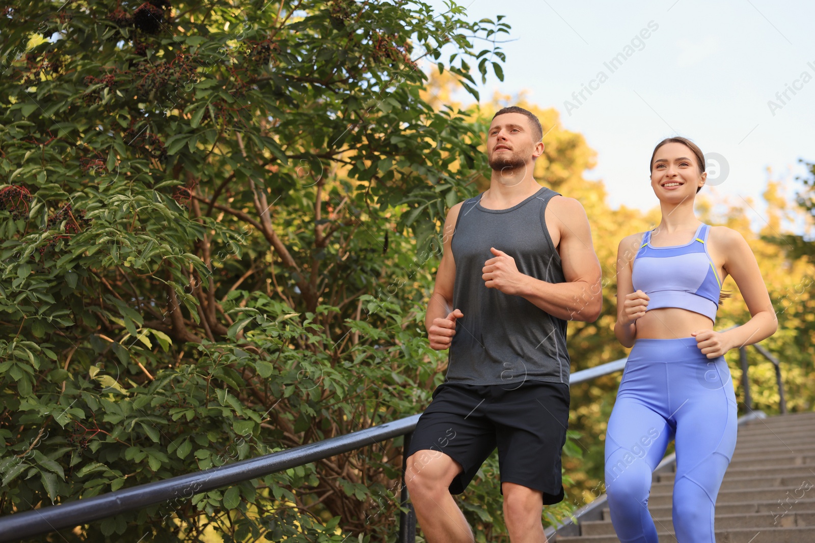 Photo of Attractive sporty couple running down stairs outdoors on sunny day