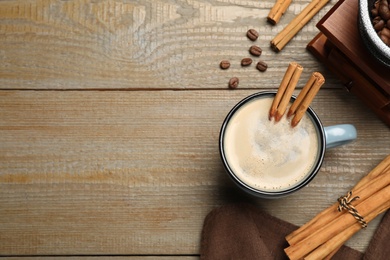 Photo of Cup of hot coffee with aromatic cinnamon on wooden table, flat lay. Space for text