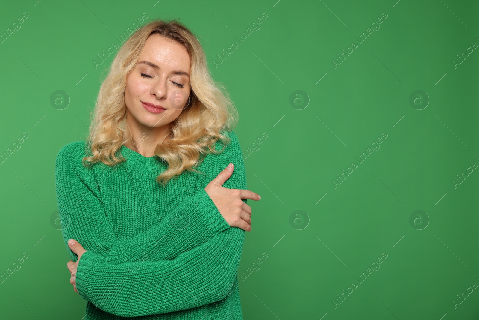 Photo of Beautiful woman in stylish warm sweater on green background. Space for text