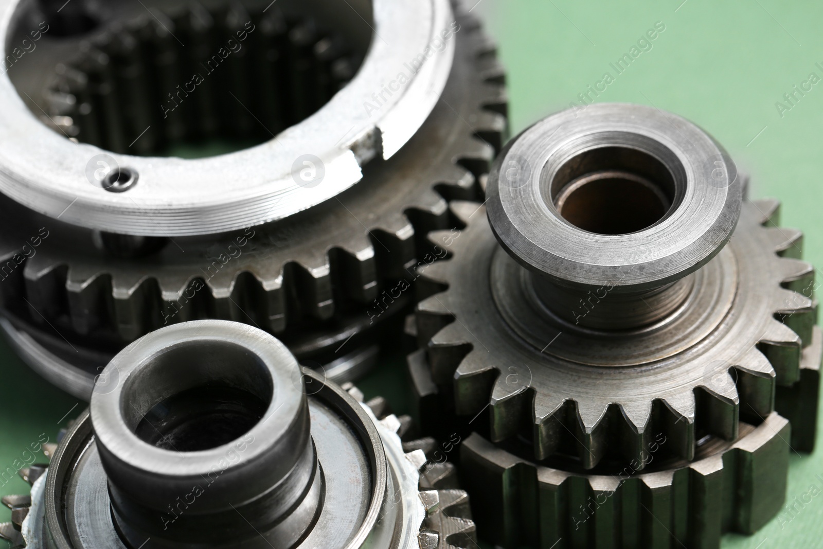 Photo of Different stainless steel gears on light green background, closeup