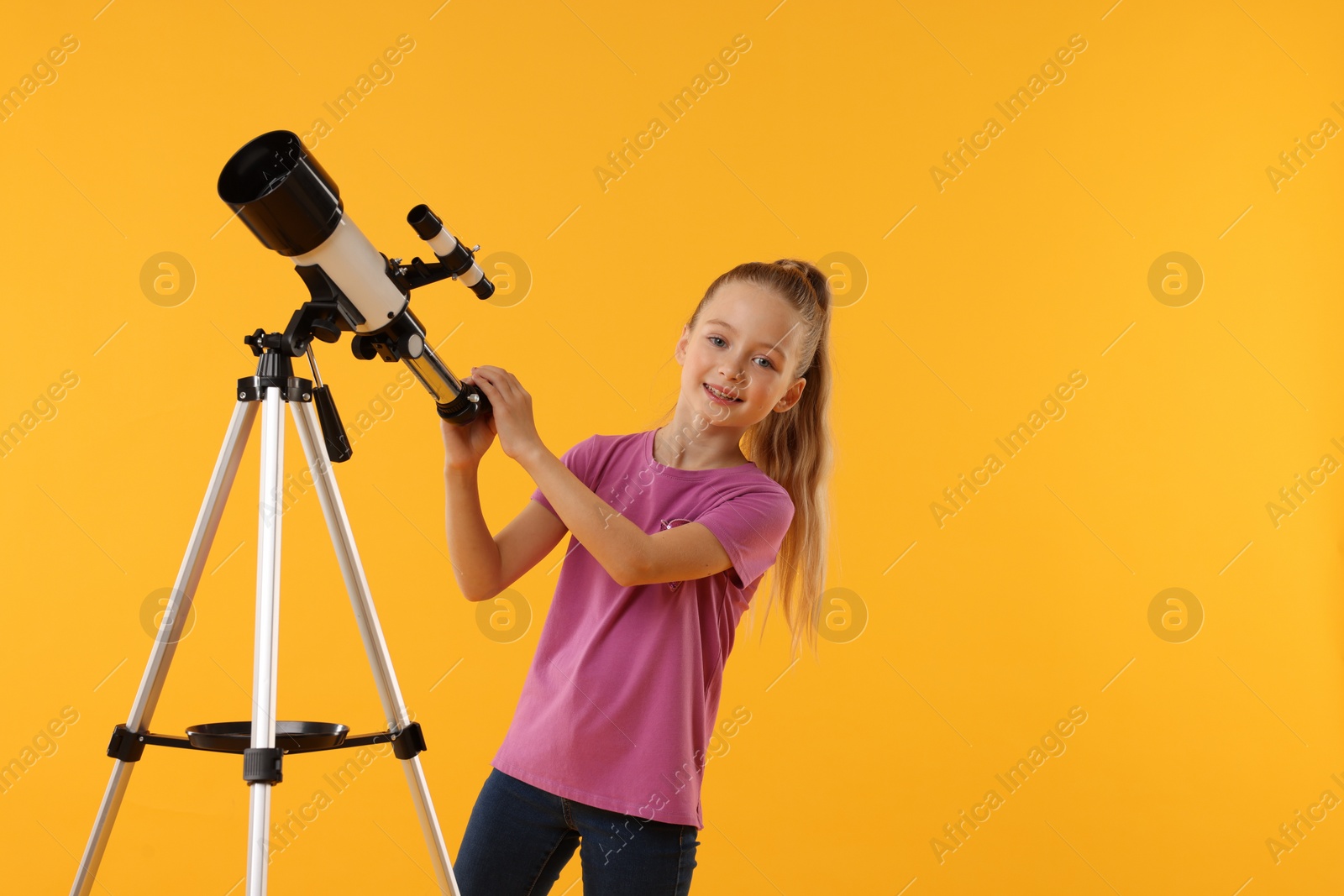 Photo of Happy little girl with telescope on orange background, space for text