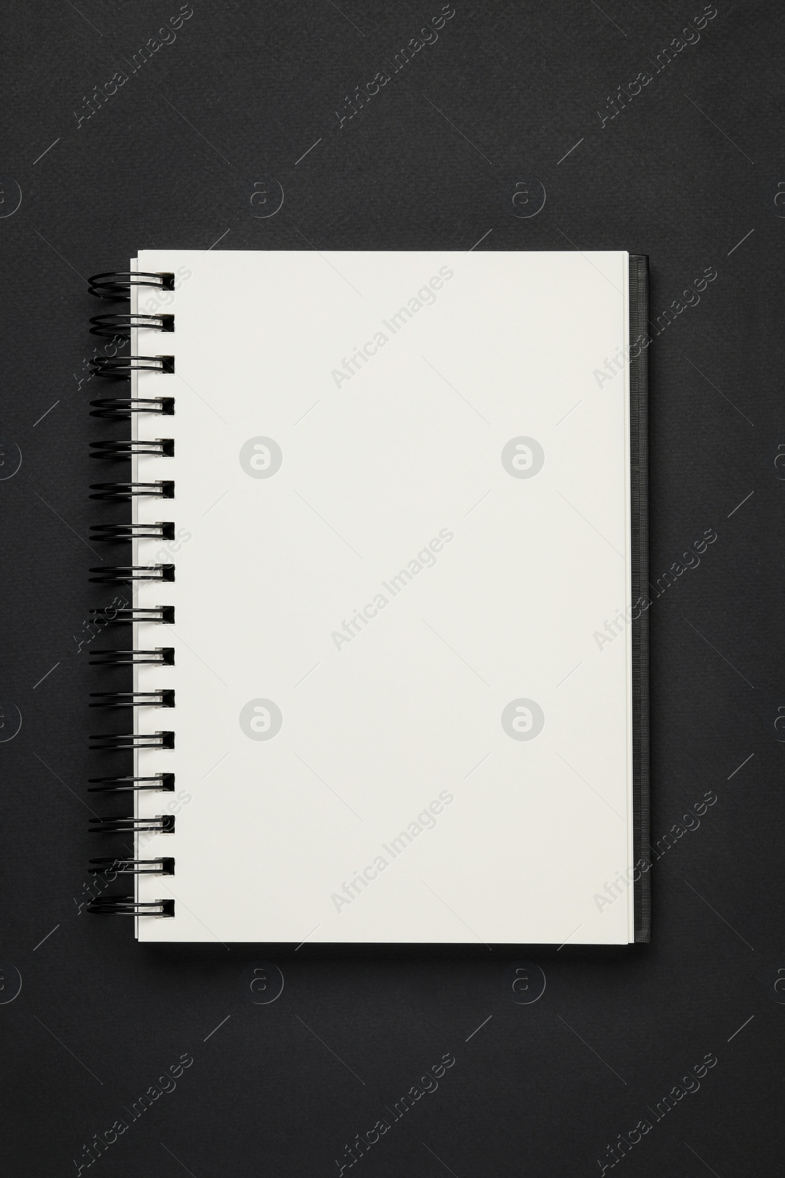 Photo of Spiral bound notebook on black background, top view