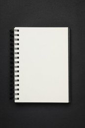 Photo of Spiral bound notebook on black background, top view