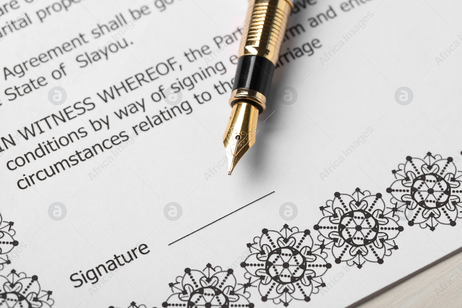 Photo of Marriage contract and pen on light wooden table, closeup