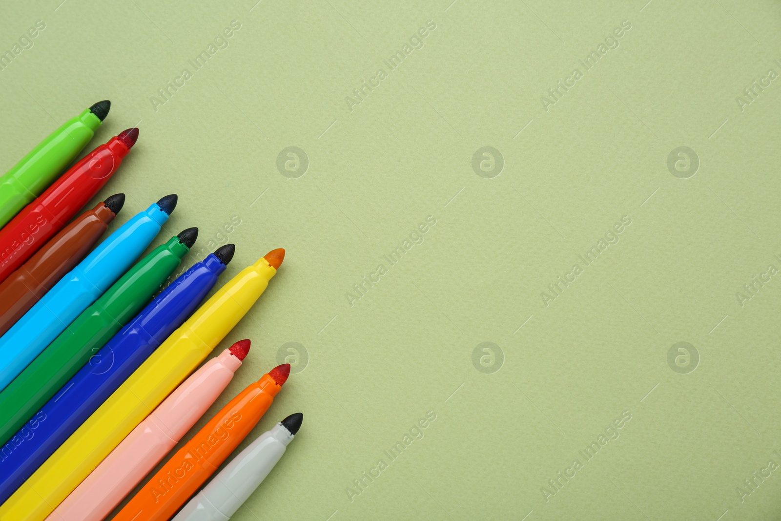 Photo of Different colorful markers on light green background, flat lay. Space for text