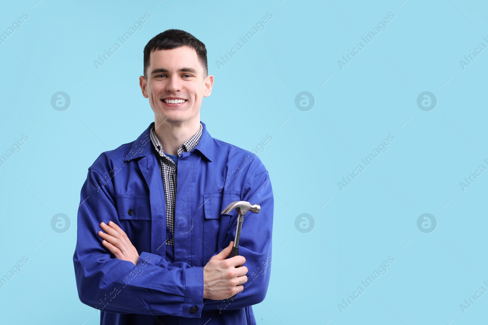 Photo of Professional repairman holding hammer on light blue background. Space for text