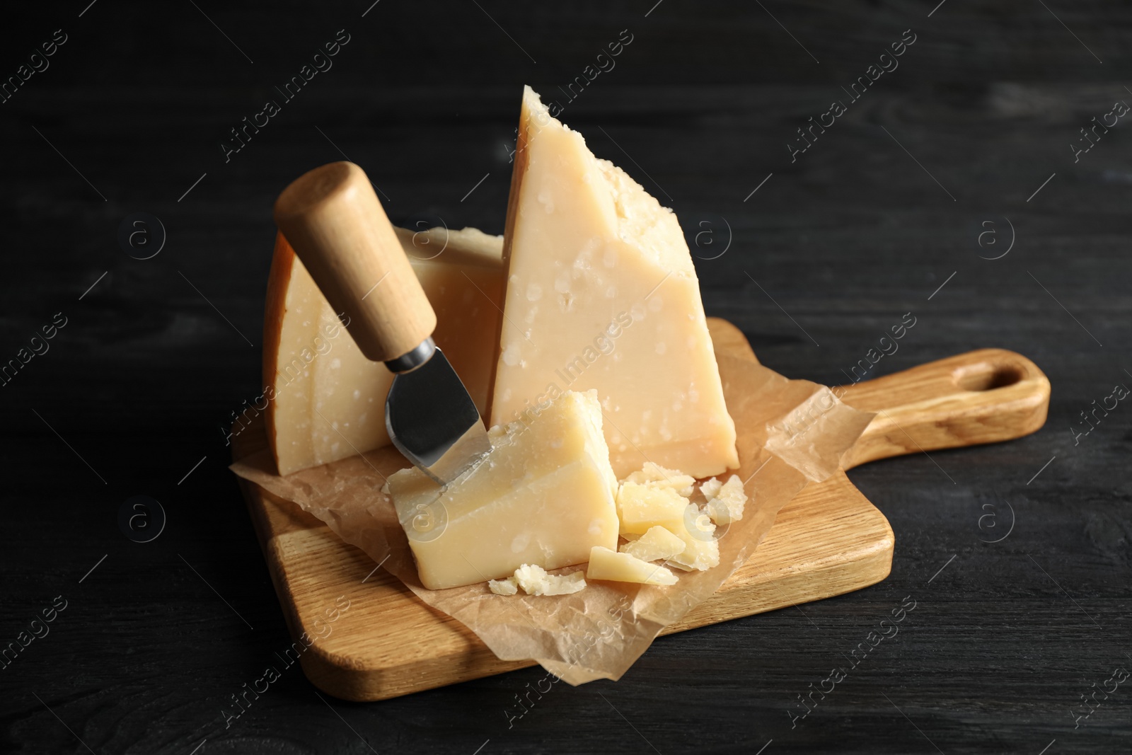 Photo of Pieces of Parmesan cheese and knife on black wooden table