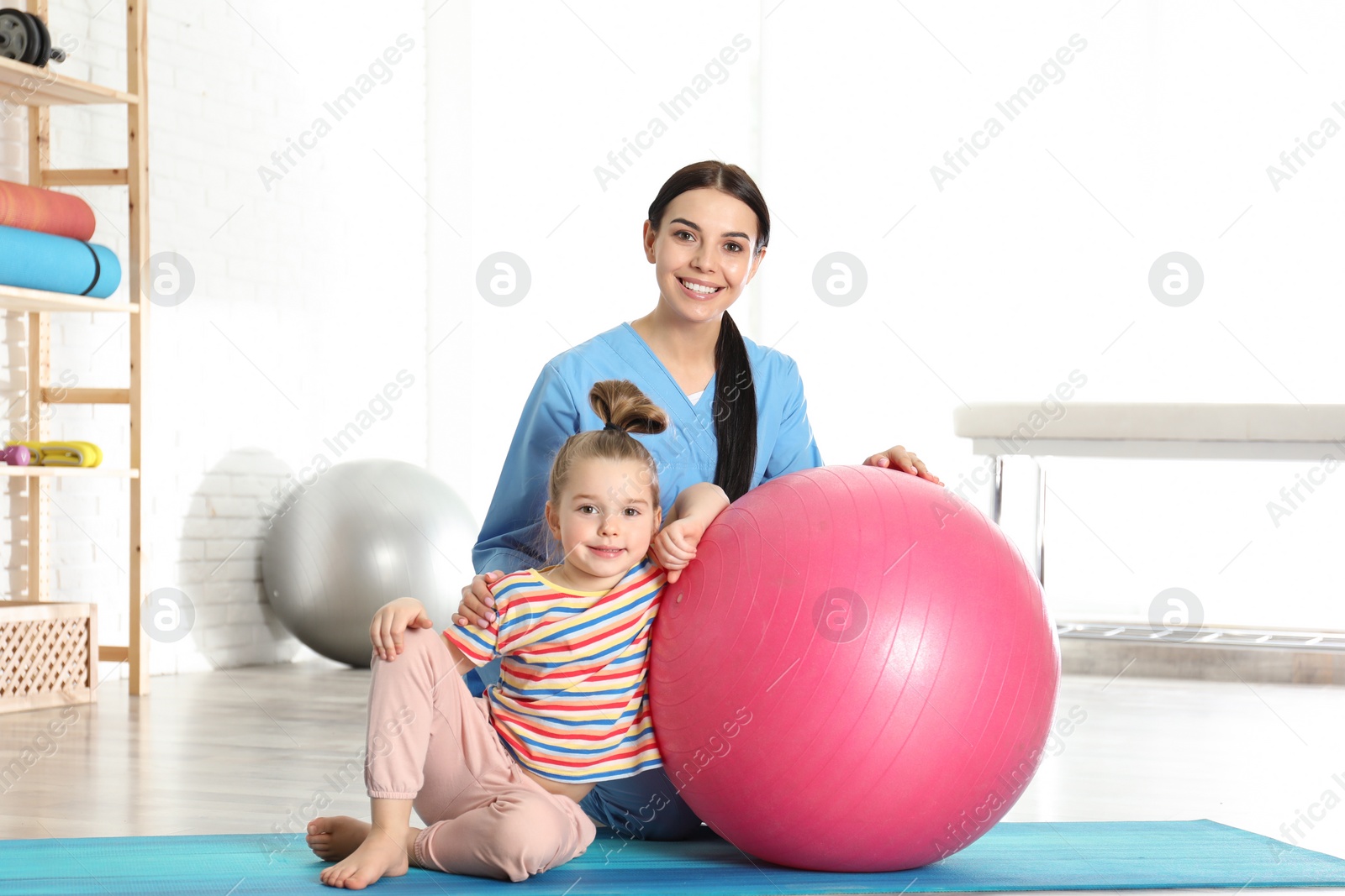 Photo of Orthopedist working with little girl in hospital gym