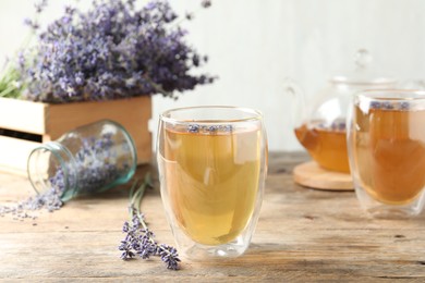 Photo of Fresh delicious tea with lavender in glass on wooden table