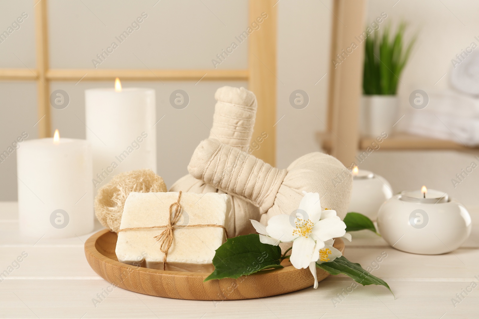 Photo of Composition with beautiful jasmine flowers and burning candles on white wooden table indoors