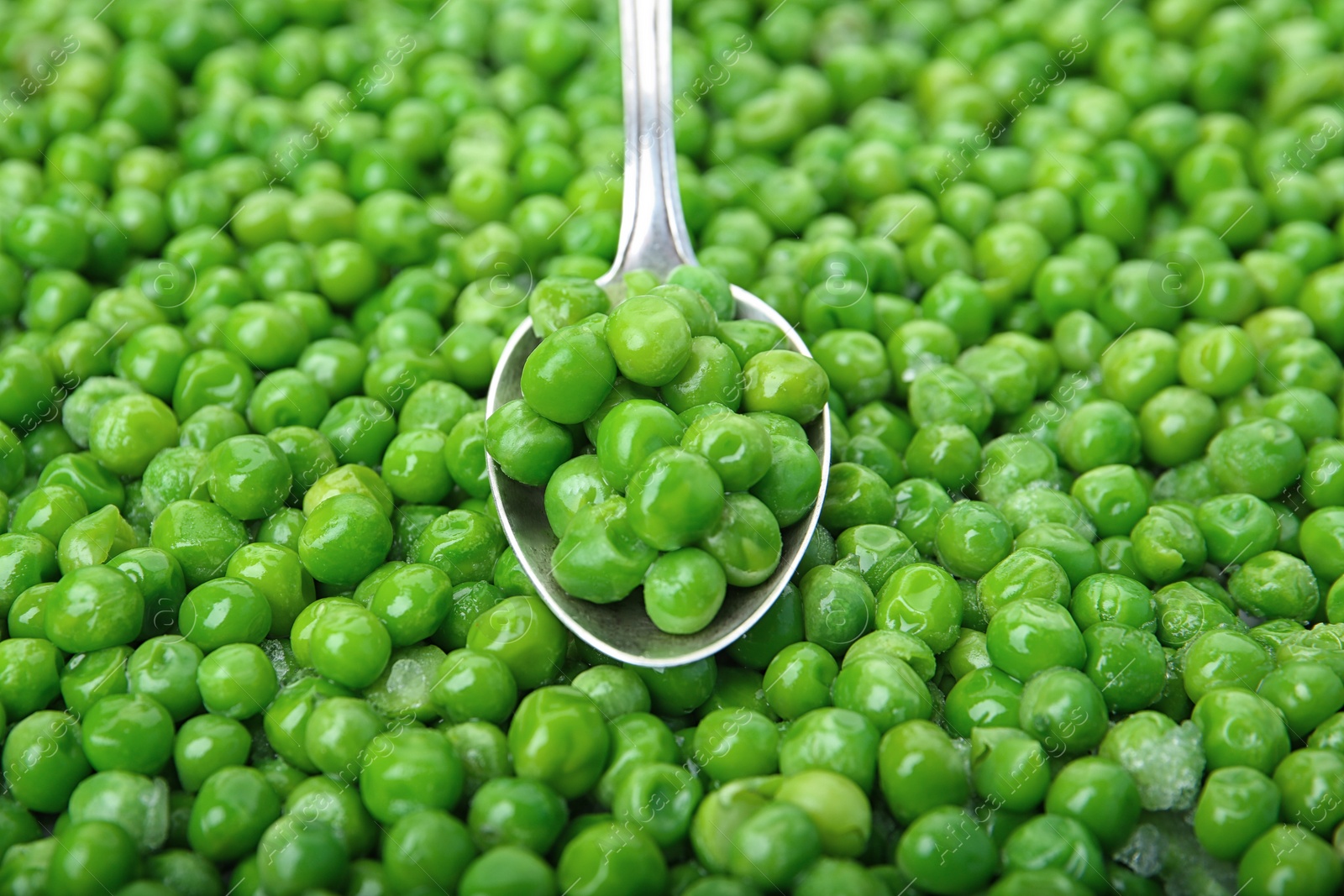 Photo of Frozen peas and spoon, closeup. Vegetable preservation