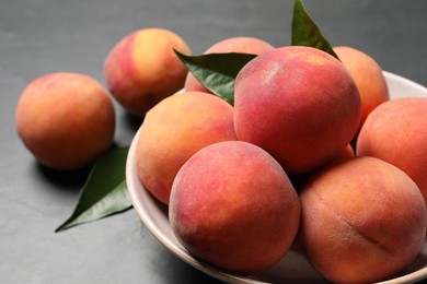Photo of Fresh peaches and leaves on grey table, closeup