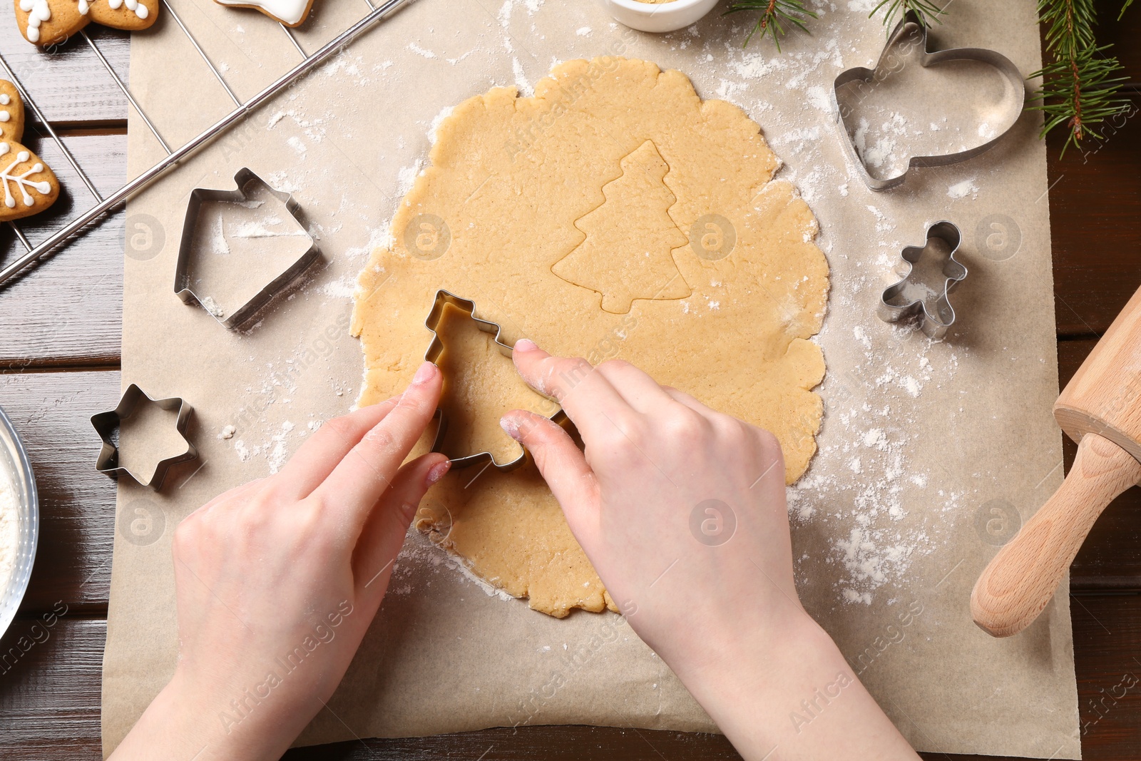 Photo of Woman making Christmas cookies with cutters at wooden table, top view