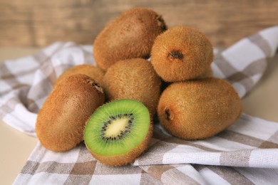 Photo of Heap of whole and cut fresh kiwis on beige table, closeup