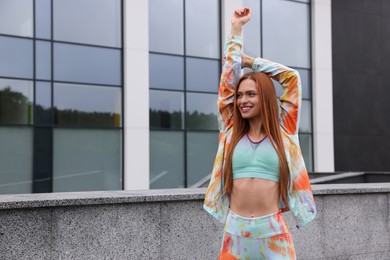 Photo of Beautiful woman in gym clothes doing exercises on street, space for text