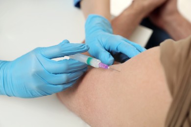 Doctor giving hepatitis vaccine to patient at table, closeup