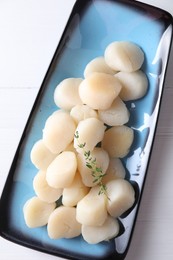 Photo of Fresh raw scallops and thyme on white wooden table, top view