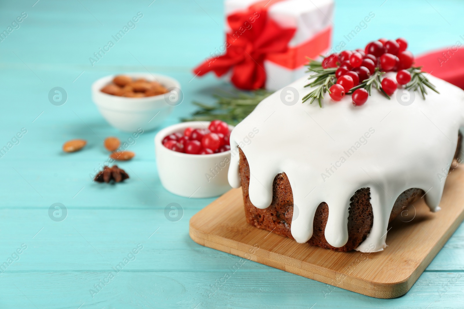 Photo of Traditional classic Christmas cake decorated with cranberries and rosemary on turquoise table. Space for text