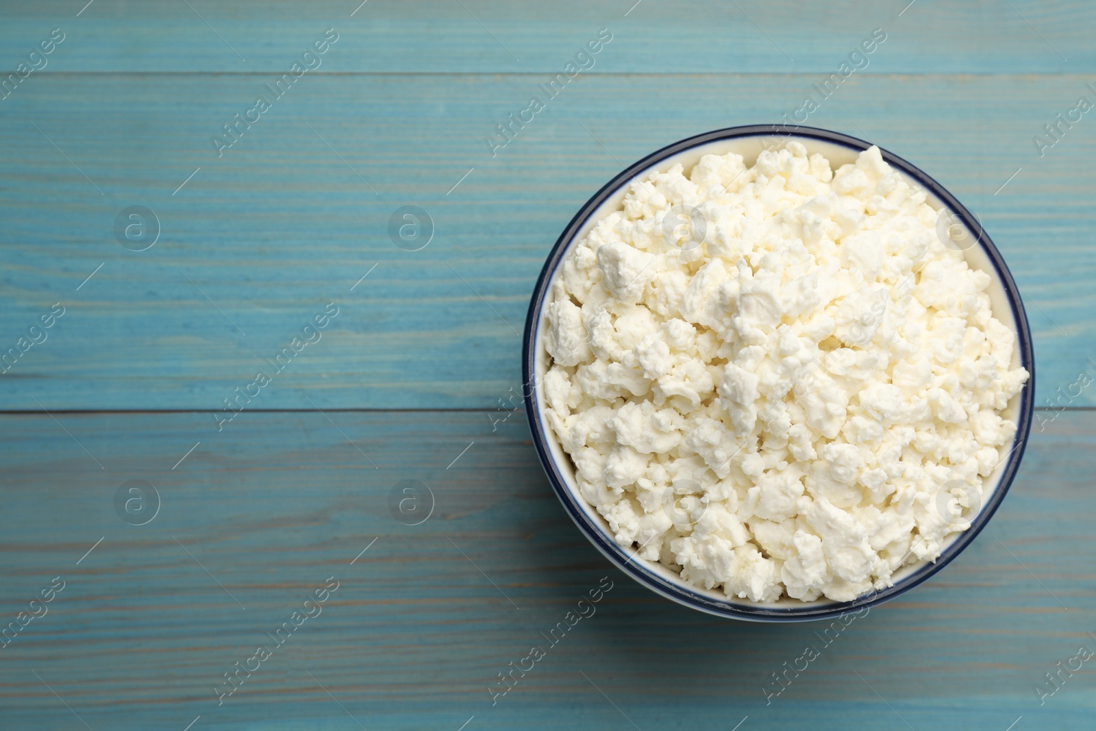 Photo of Delicious fresh cottage cheese on blue wooden table, top view. Space for text