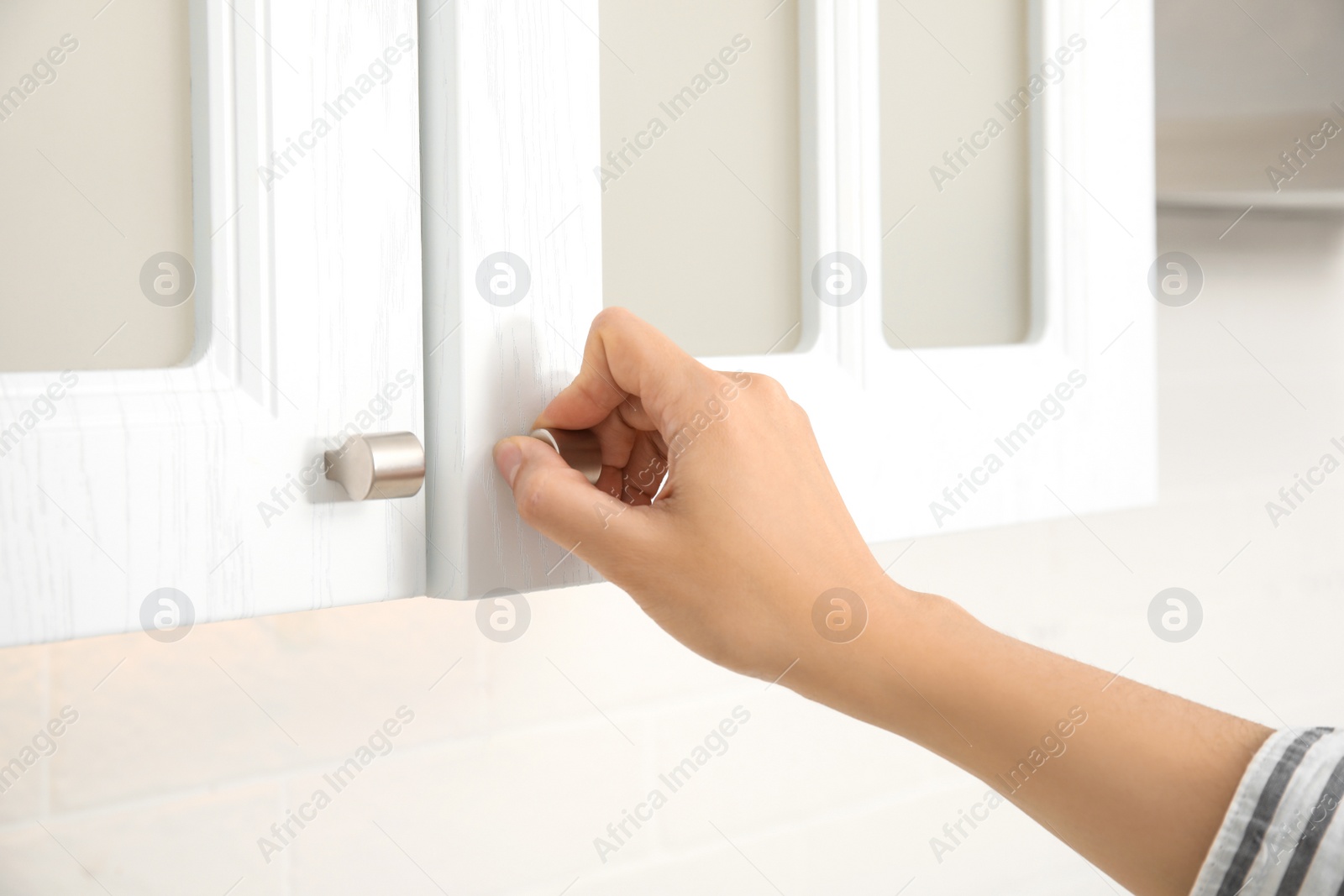 Photo of Woman opening cabinet door at home, closeup