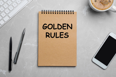 Image of Flat lay composition of notebook with phrase GOLDEN RULES and cup of coffee on grey background