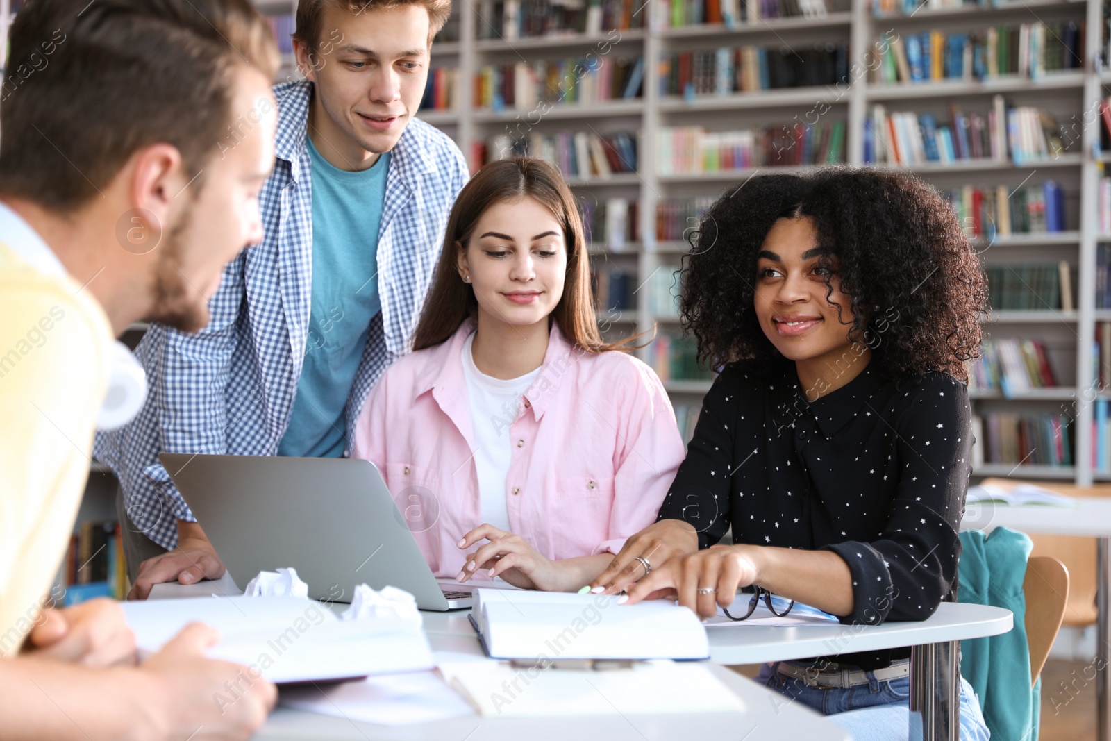 Photo of Group of young people studying at table in library