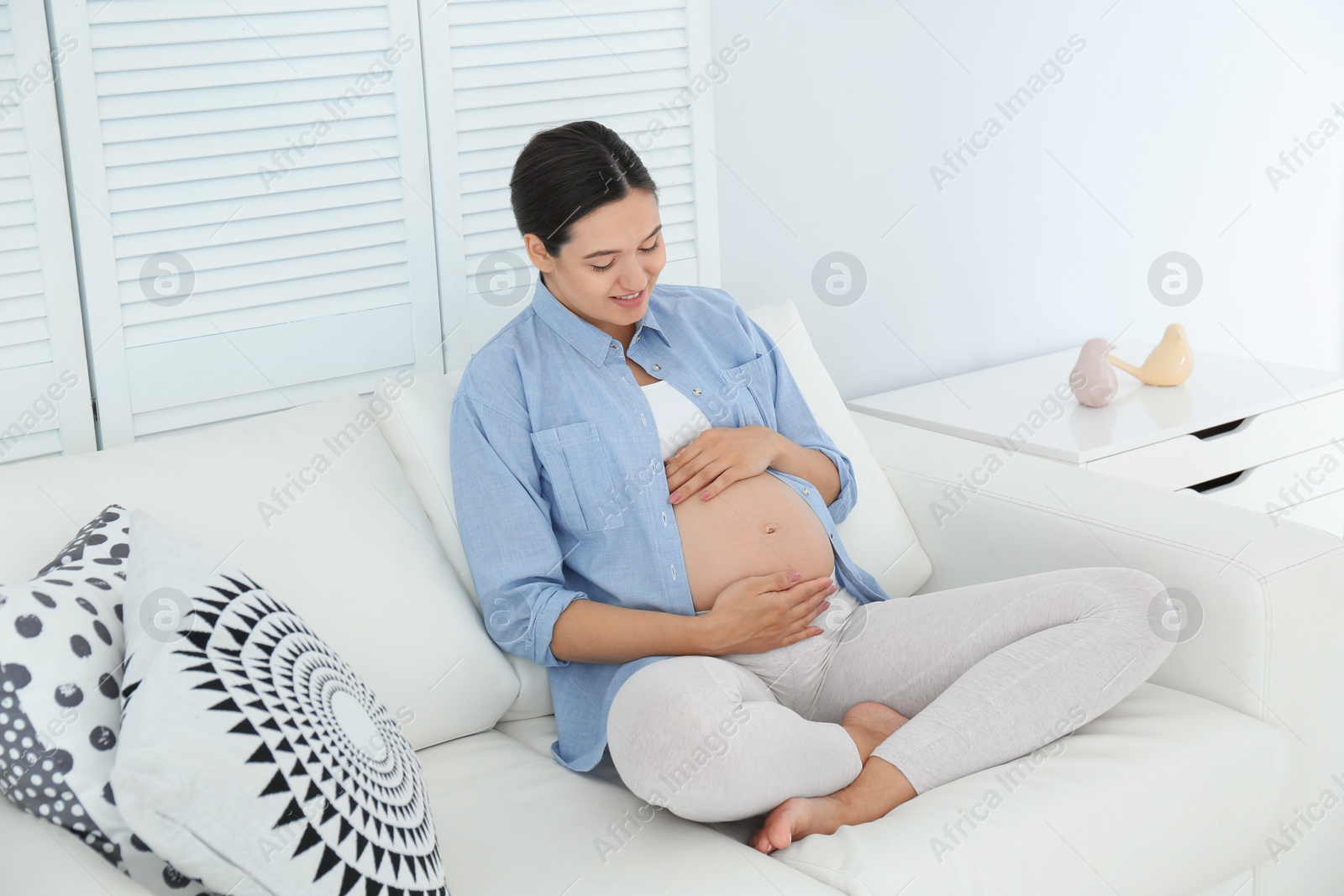 Photo of Beautiful pregnant woman sitting on sofa at home