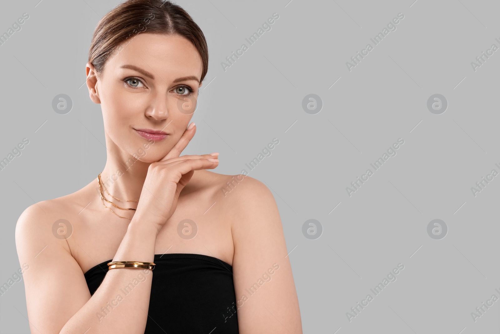 Photo of Beautiful woman with elegant jewelry on light grey background. Space for text