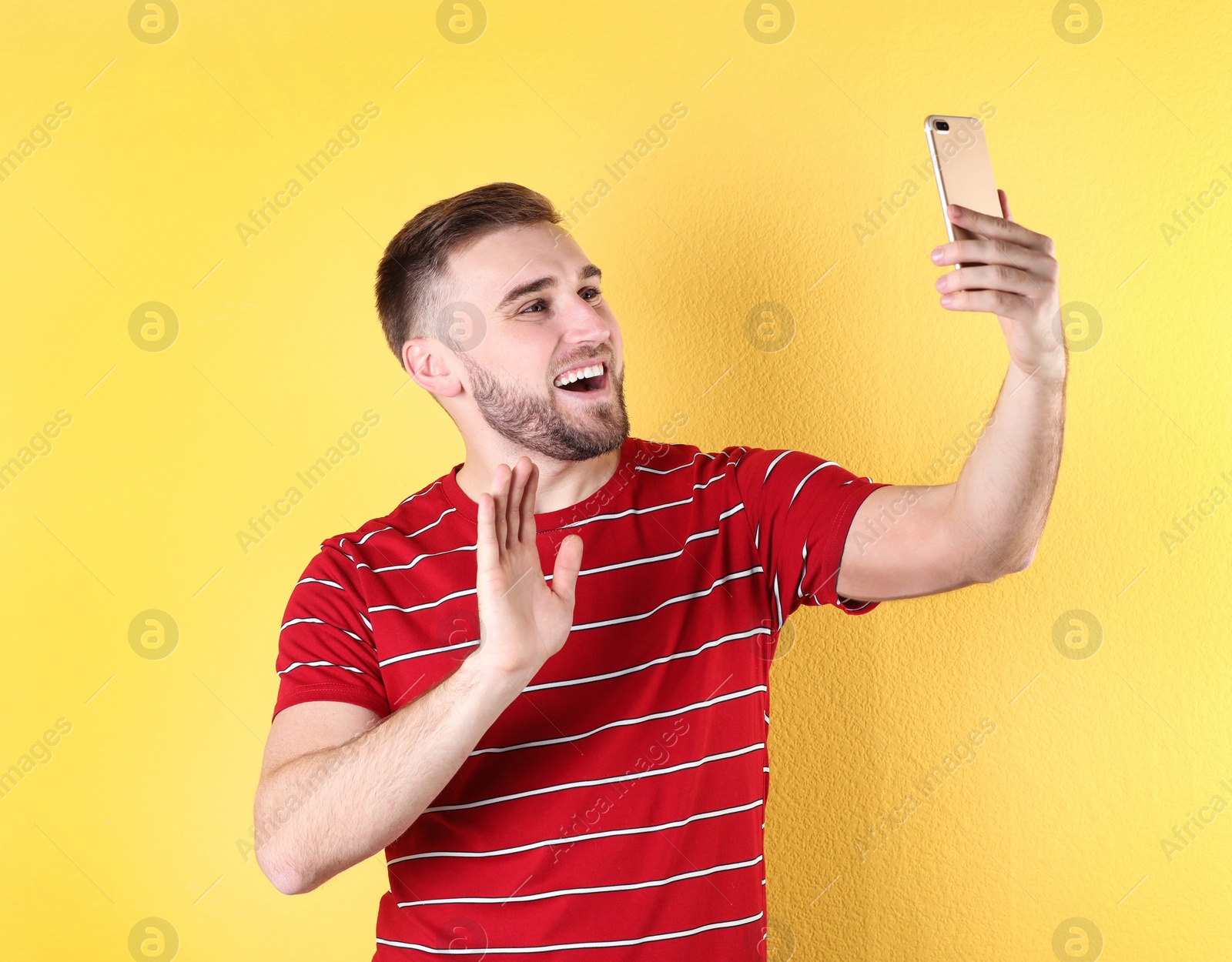 Photo of Young man using video chat on smartphone against color background