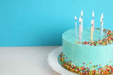 Photo of Fresh delicious birthday cake with candles on table against color background. Space for text