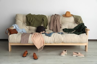 Messy pile of clothes and accessories on sofa in living room