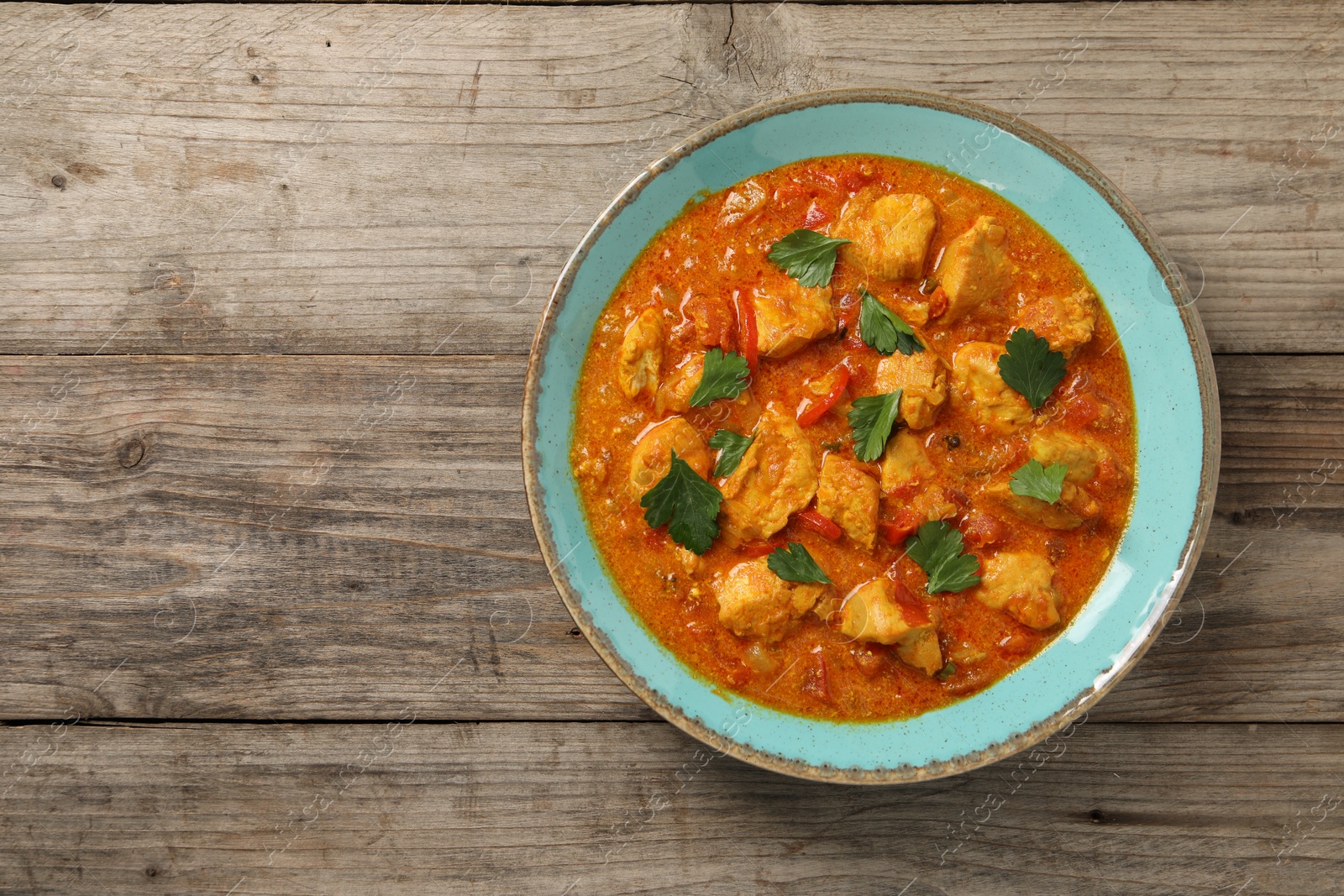 Photo of Delicious chicken curry on wooden table, top view. Space for text