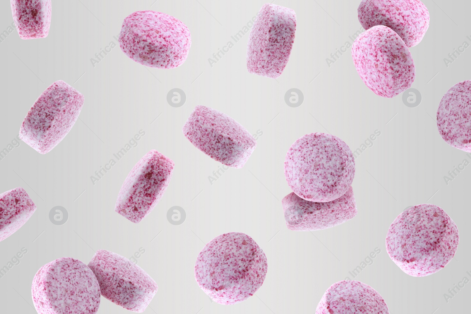 Image of Vitamin. Pink tablets falling on light grey background