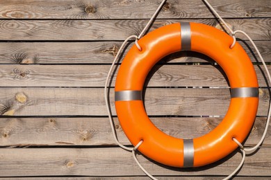 Photo of Orange life buoy hanging on wooden wall, space for text