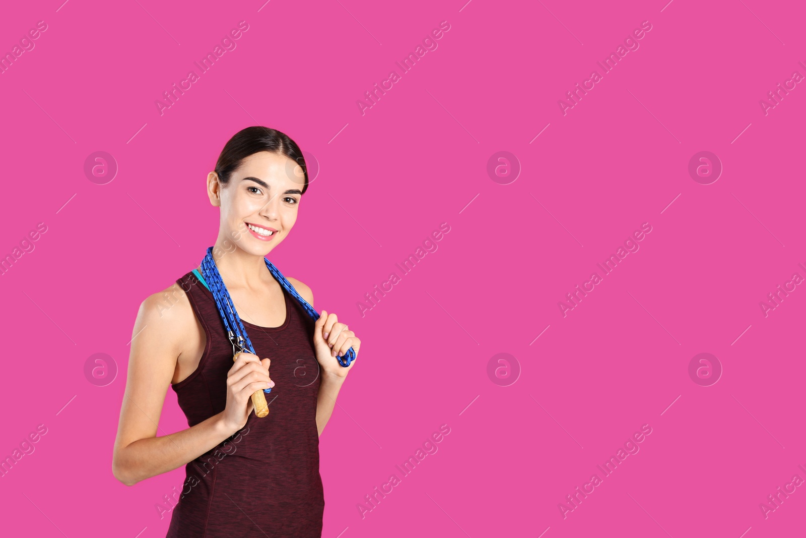 Photo of Portrait of young sportive woman with jump rope on color background. Space for text