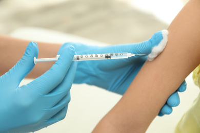 Doctor vaccinating little child in clinic, closeup