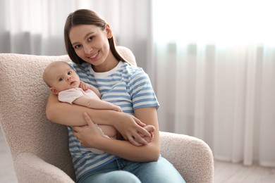 Photo of Mother with her cute baby in armchair at home, space for text