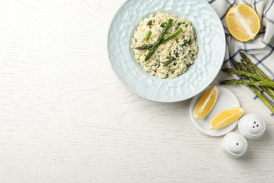 Photo of Delicious risotto with asparagus on white wooden table, flat lay. Space for text