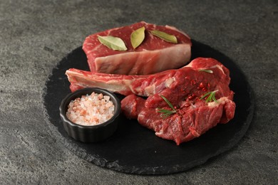 Pieces of raw beef meat and spices on grey textured table