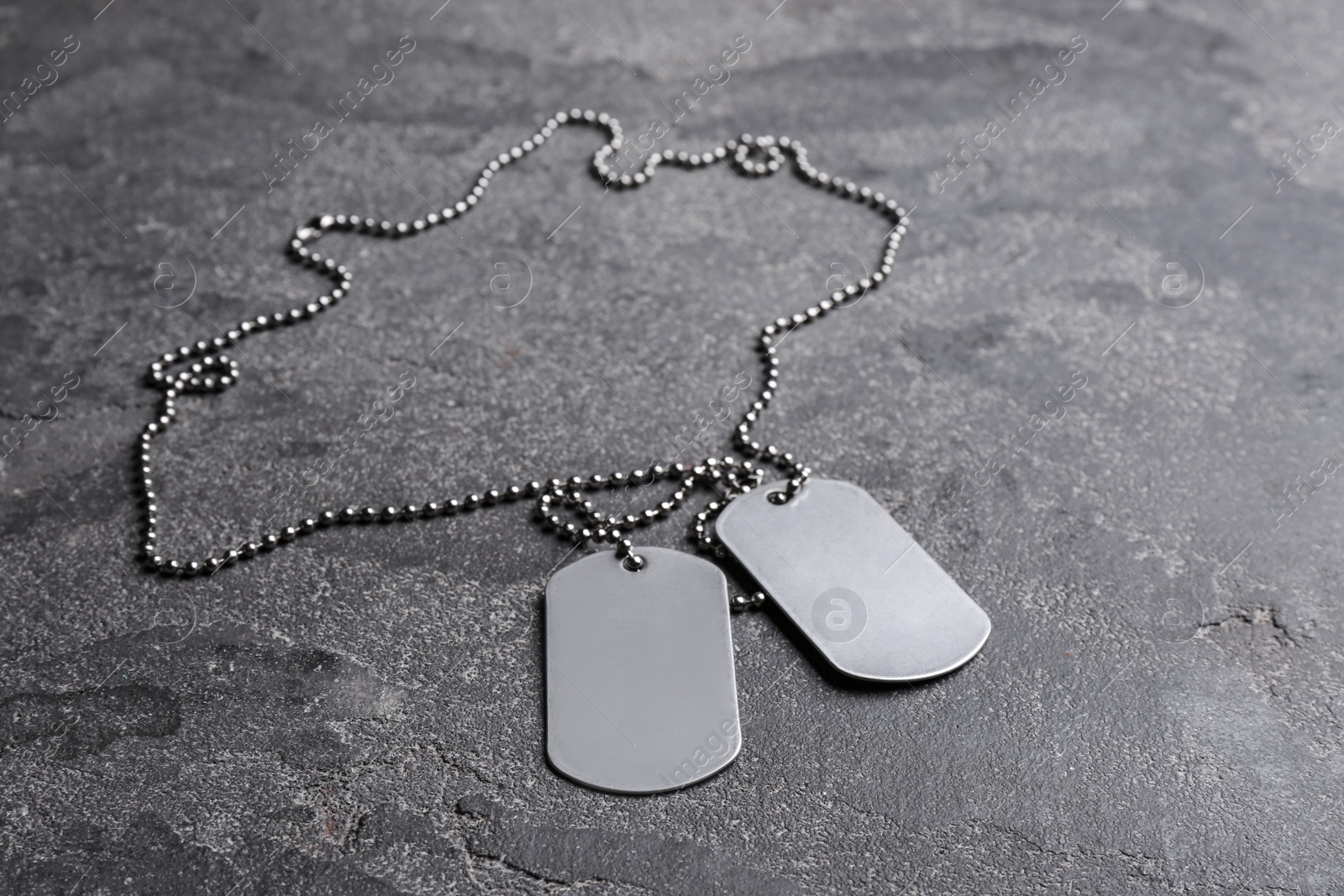 Photo of Blank military ID tags on grey stone surface, space for text