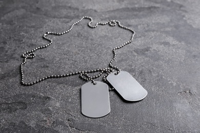 Blank military ID tags on grey stone surface, space for text