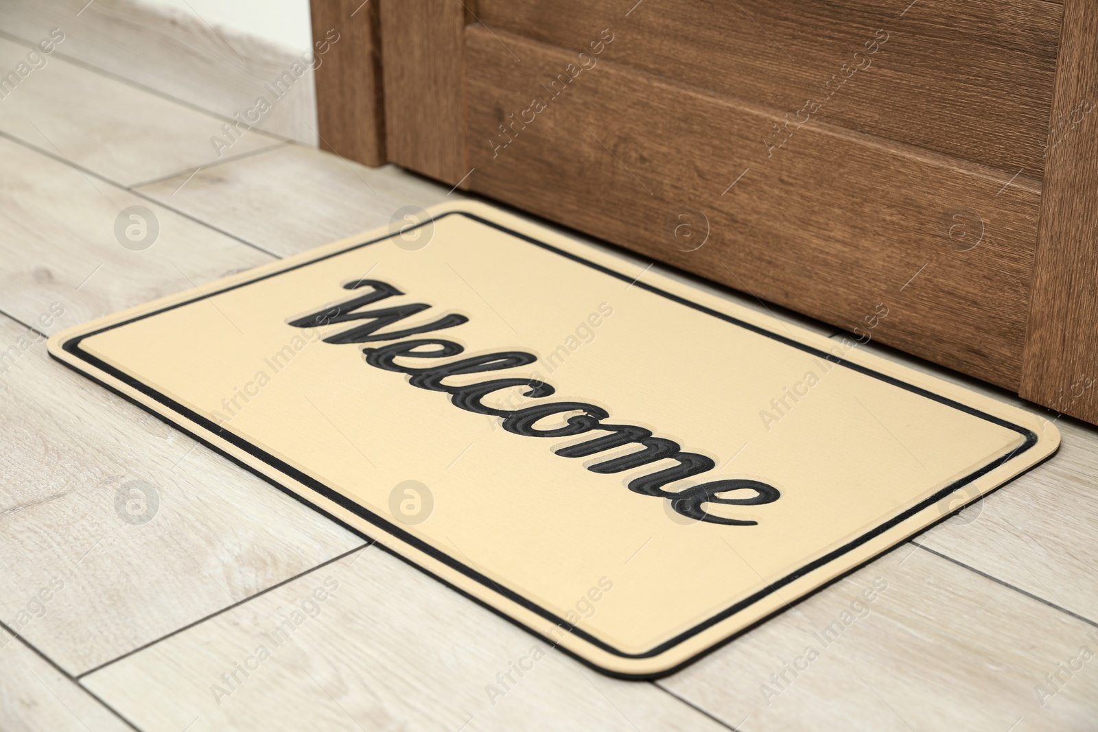 Photo of Beautiful beige doormat with word Welcome on floor near entrance