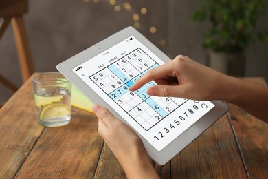 Image of Woman playing sudoku game on tablet indoors, closeup