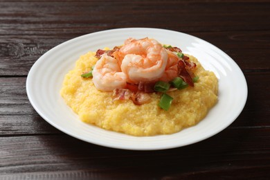 Photo of Plate with fresh tasty shrimps, bacon, grits and green onion on dark wooden table