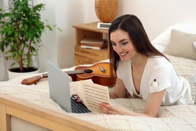 Woman learning to play ukulele with online music course at home. Time for hobby