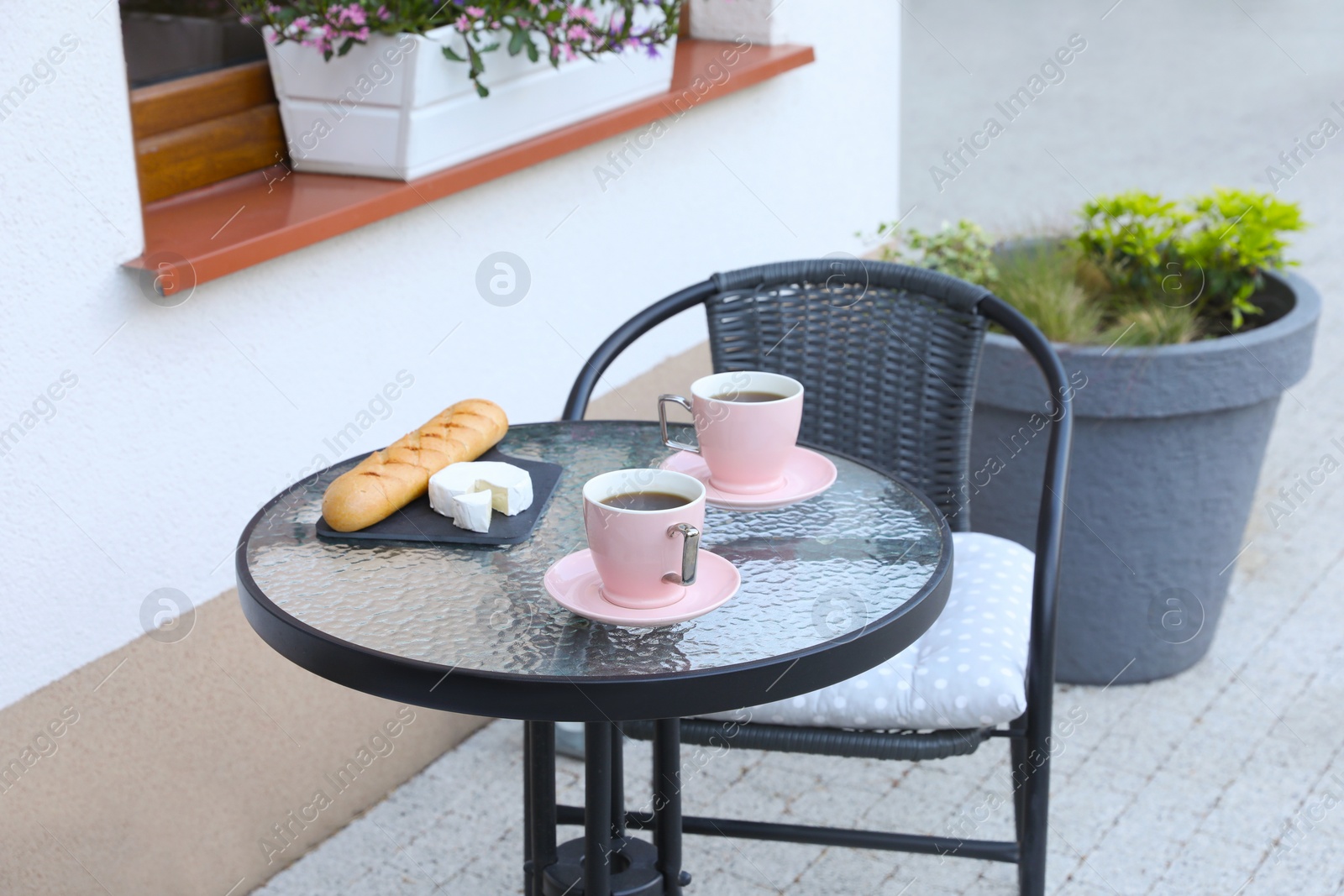 Photo of Cups of coffee, bread and cheese on glass table. Relaxing place at outdoor terrace